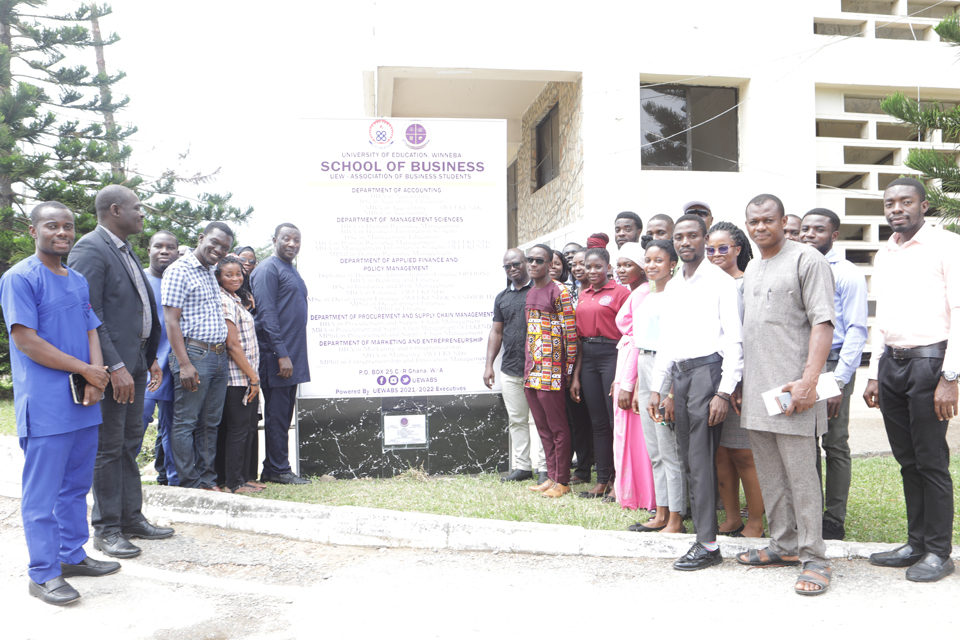 Faculty members sandwich the automated signpost in a group photograph