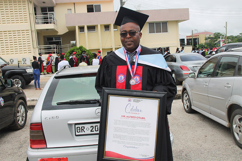 Mr. Alfred Otabil holds up the certificate he received from UEW for being named the best worker in the senior staff category