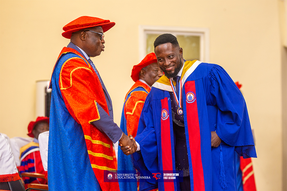 The Vice-Chancellor (right) is congratulating the valedictorian (left) with a handshake.